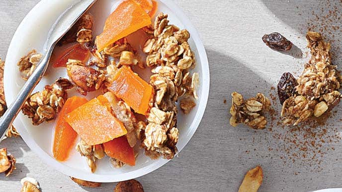 Mango-Chai Granola in a small white bowl with a metal spoon