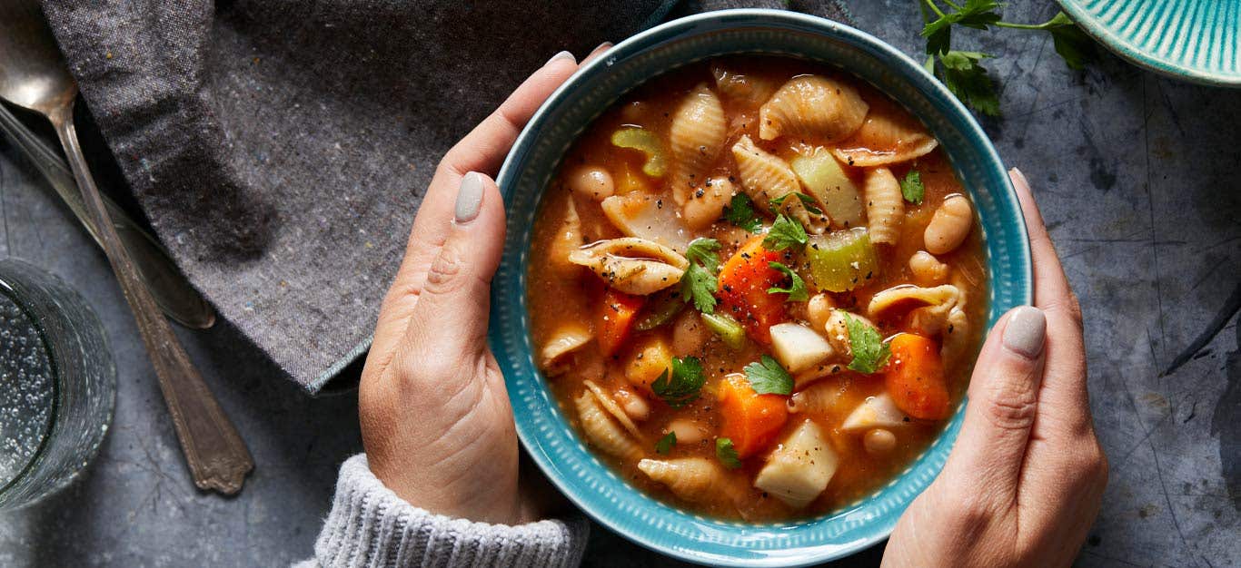 Harvest Vegetable Instant Pot Minestrone in a blue bowl being held in a woman's hands