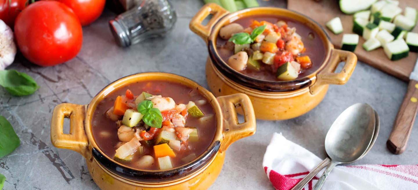 Two bowls of vegan minestrone on a table