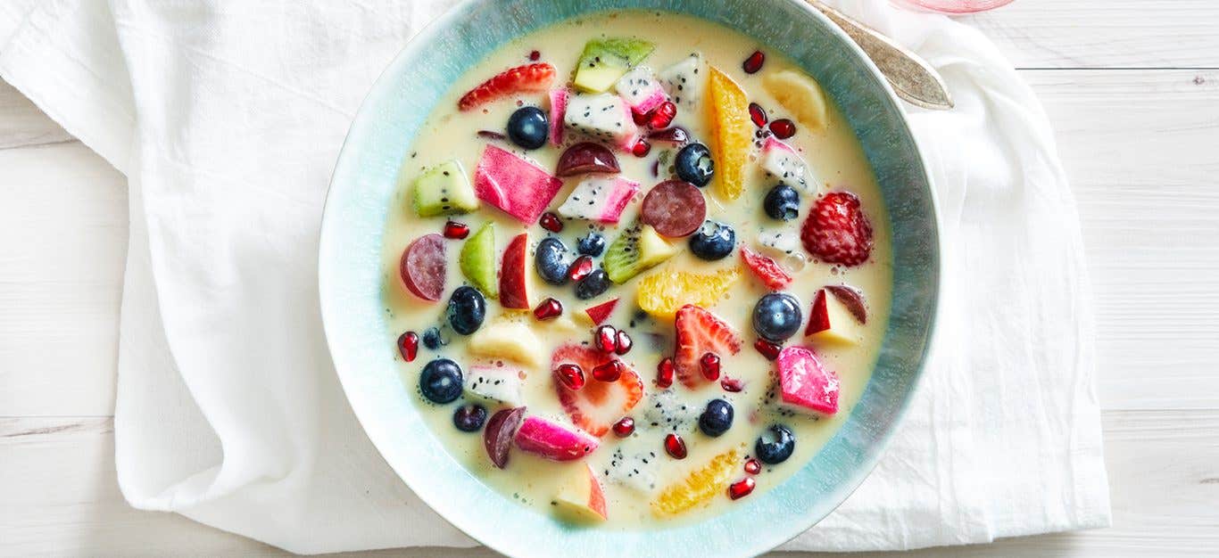 A bowl of Mixed Fruit Soup filled with fresh strawberries, orange slices, blueberries, and other fruits