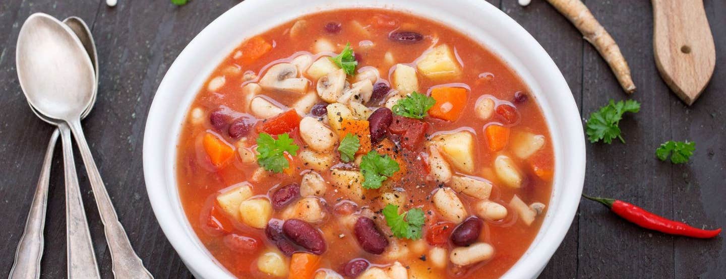 Mixed Beans and Root Vegetable Stew in a white bowl on a dark wooden table top