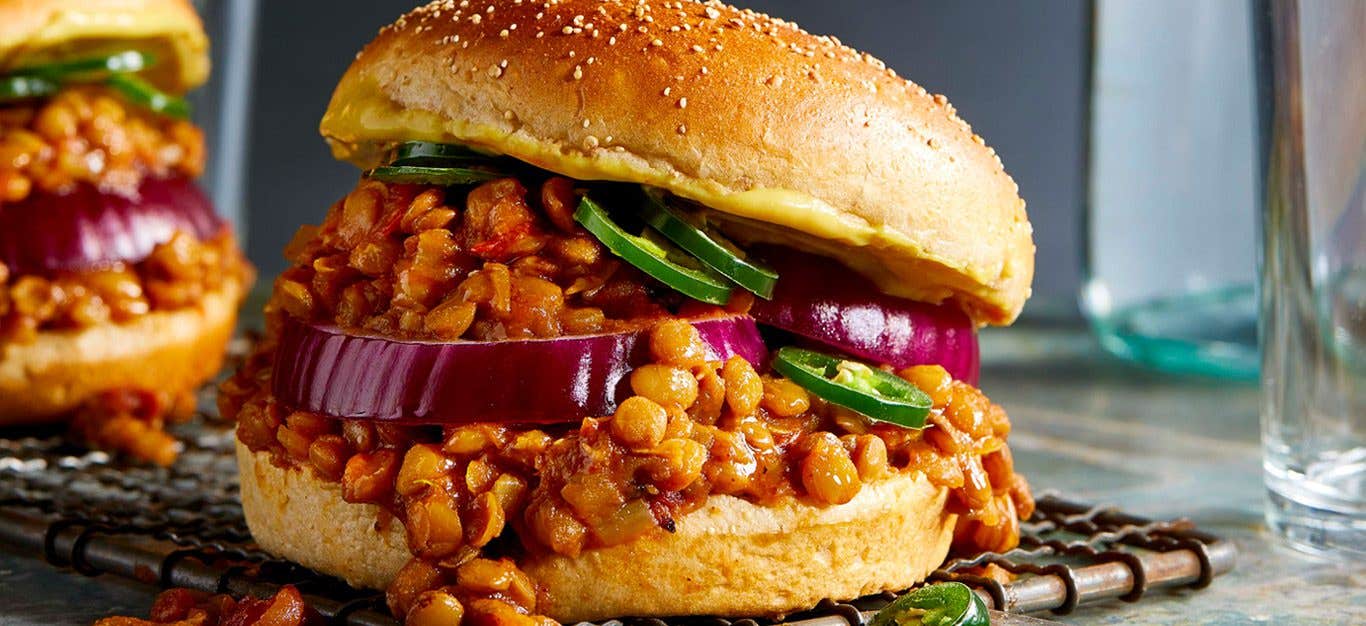 Close-up shot of a lentil sloppy joe with filling spilling out of bun