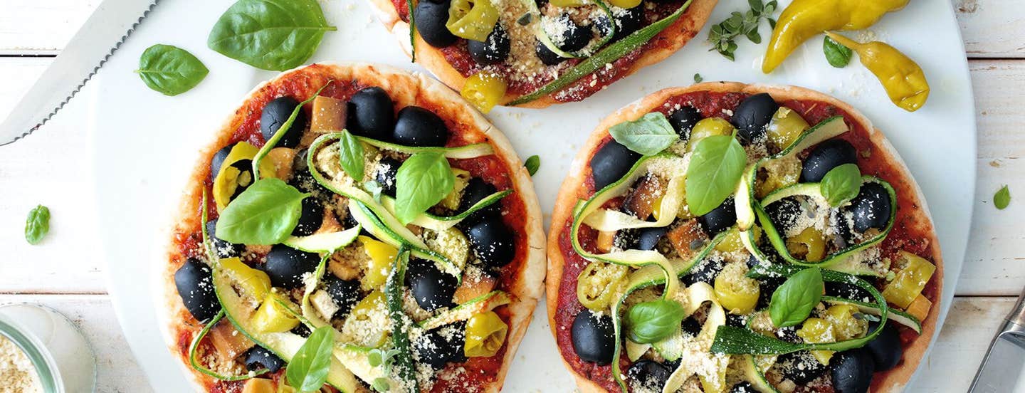 Three Vegan Pita Pizzas on a round marble chopping board