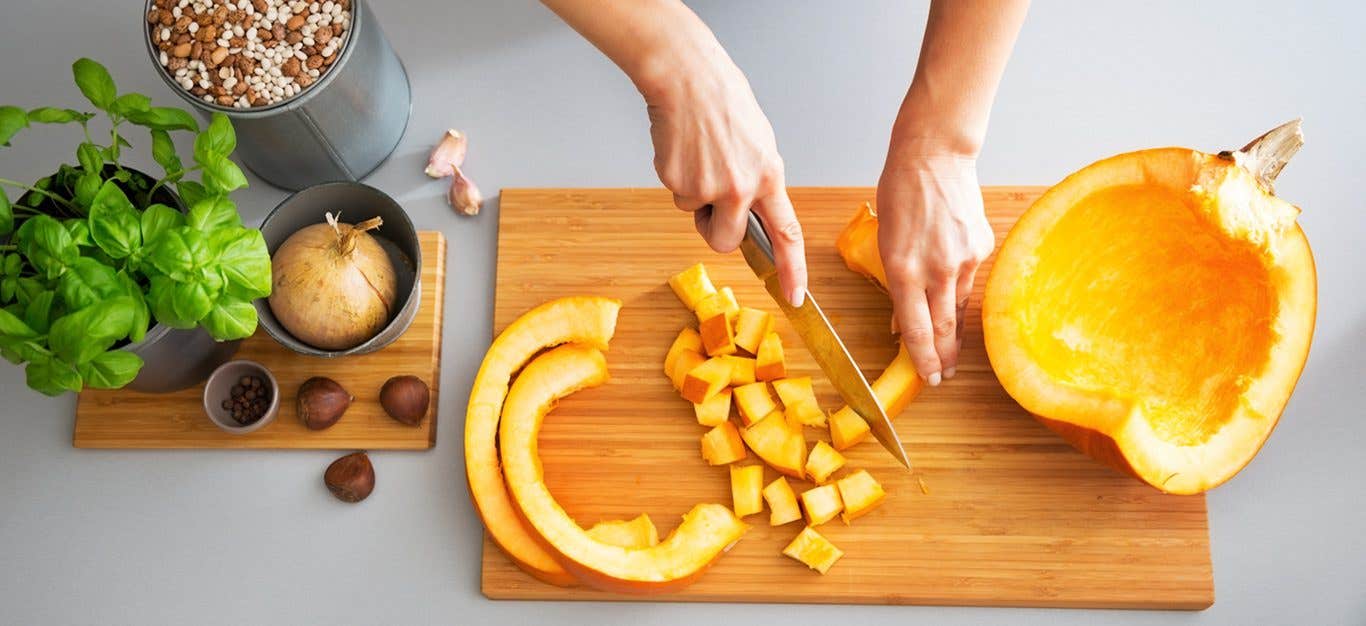 Woman cutting pumpkins on a cutting board, preparing to cook