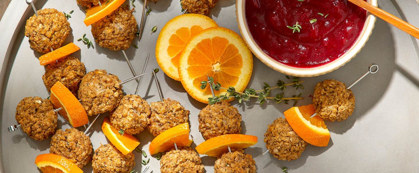 Savory Vegan Meatballs on a serving platter with a side dish of Cranberry Glaze