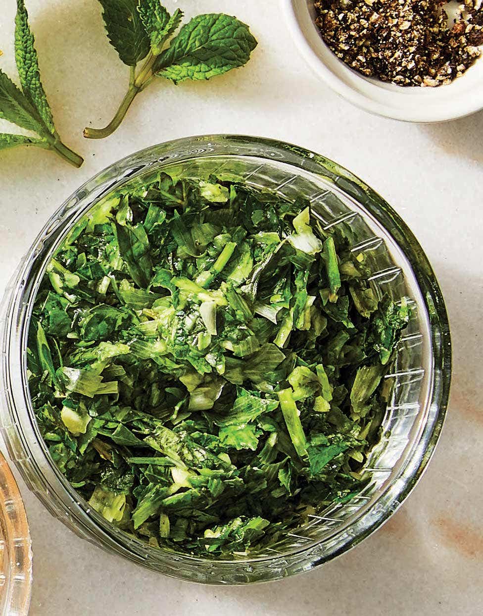 A green, herby oil-free smashed garlic and herb dressing shown in a small glass bowl