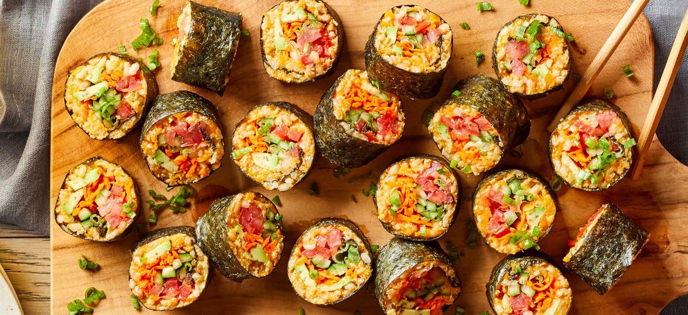 spicy tomato sushi rolls on a wooden cutting board with chopsticks in the right corner