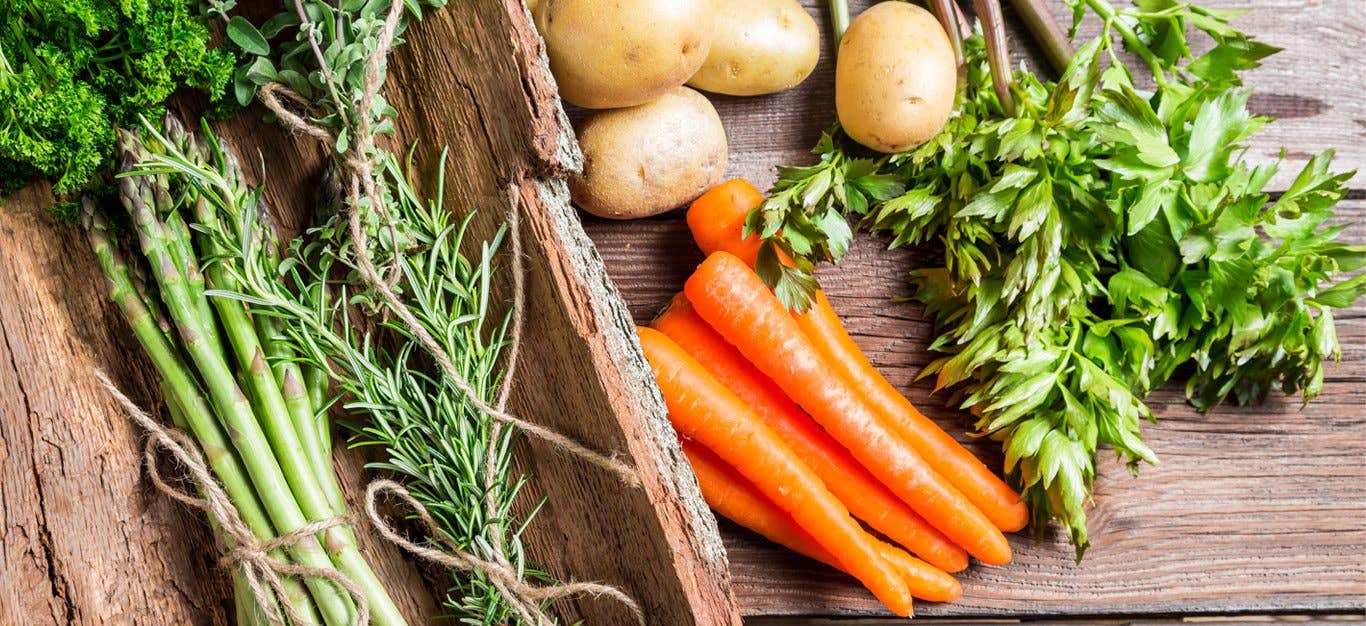 Spring vegetables on wooden background - asparagus carrots and herbs