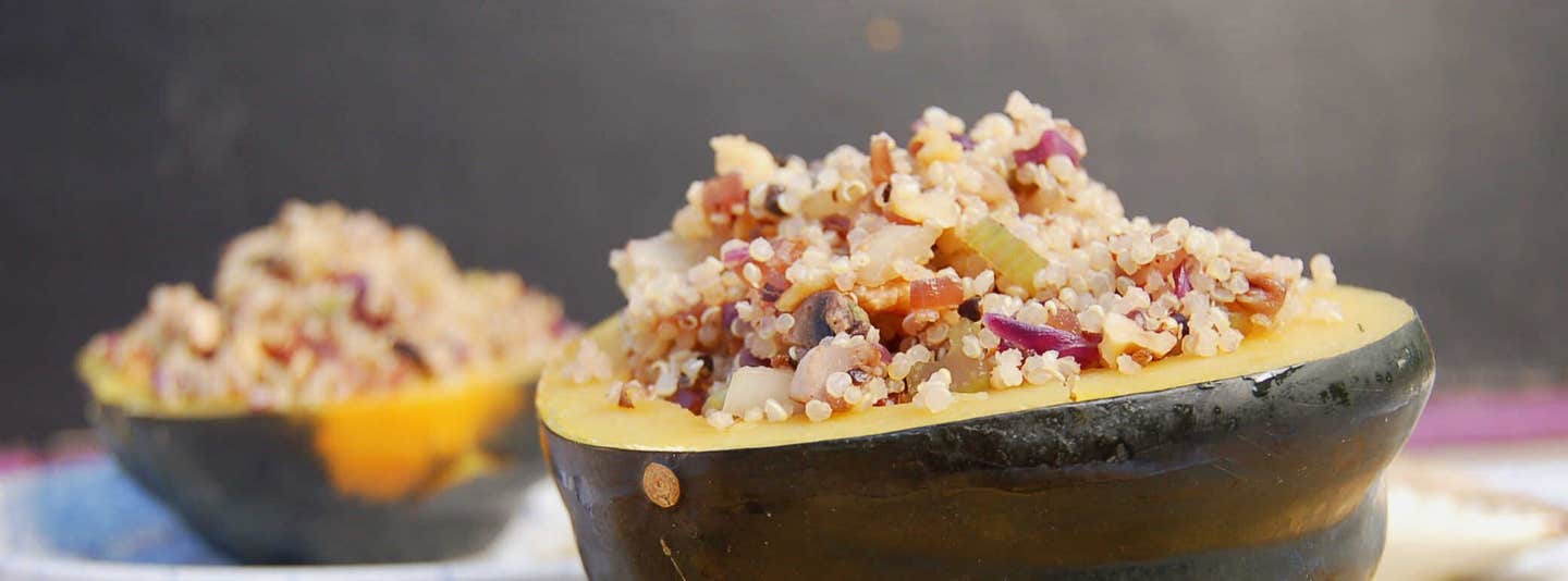 Easy Stuffed Acorn Squash on a chopping board with sprigs of rosemary. Another plate of squash is faded into the background