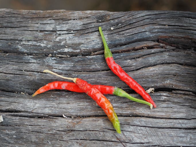 Three thai bird chiles shown on a wooden background