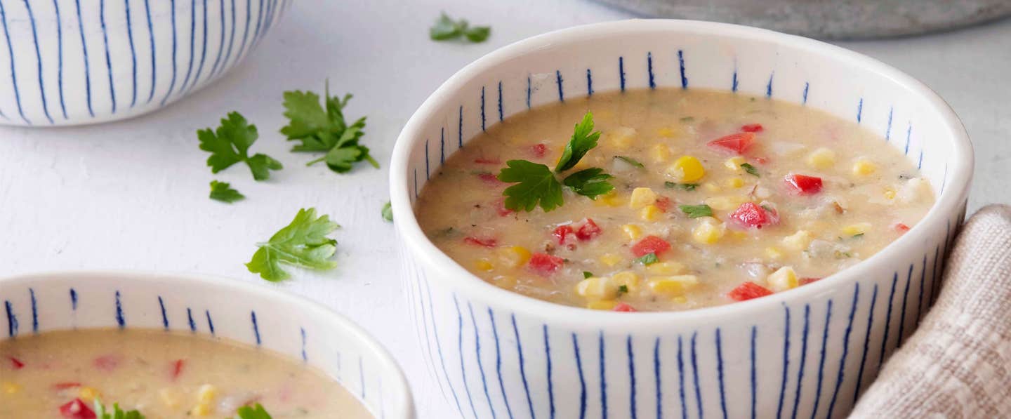 Easy Vegan Corn Chowder in a rustic white bowl with blue stripes