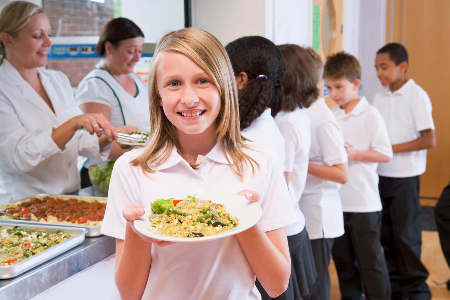 Schoolgirl holding plate of vegan lunch in school cafeteria