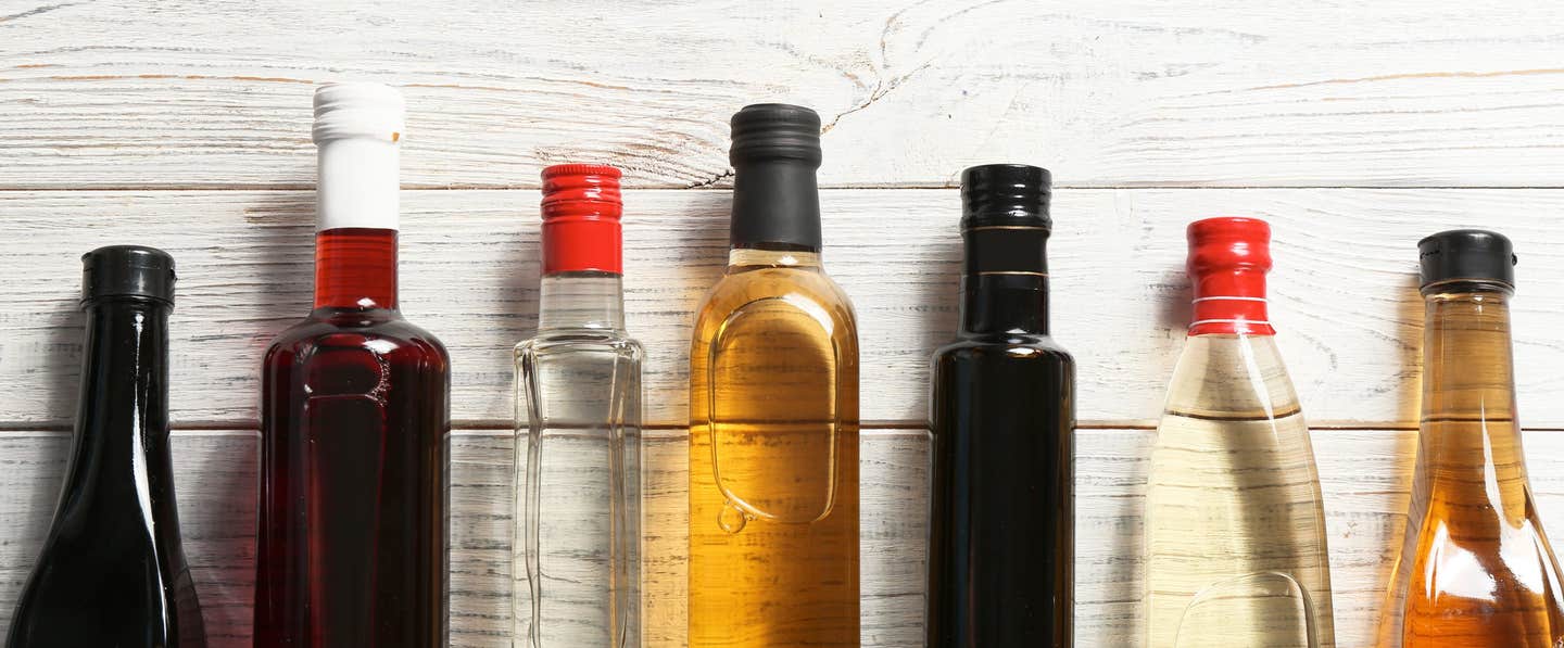 Seven unlabelled bottles of various vinegars.