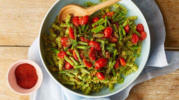 Creamy Avocado-Kale Pasta in a blue bowl next to a small bowl of paprika